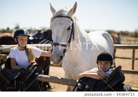 Two girls standing next to the white horse in the ranch Two girls standing next to the white horse in the ranch 34364715