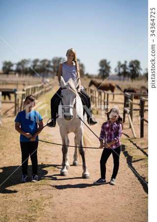 Kids riding a horse in the ranch 34364725