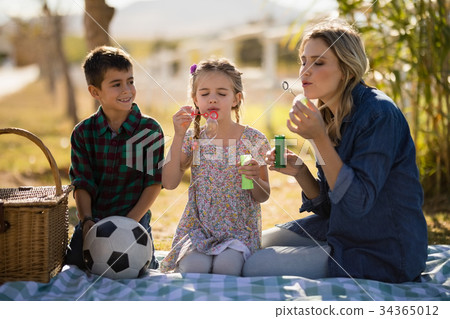 Family blowing bubble in park 34365012