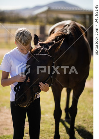 Smiling girl caressing the horse in the ranch 34365148