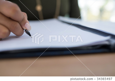 Female executive writing on a document at desk in the office 34365497