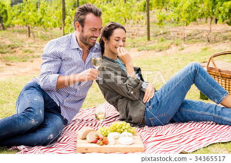 Smiling man with woman having wine at lawn 34365517