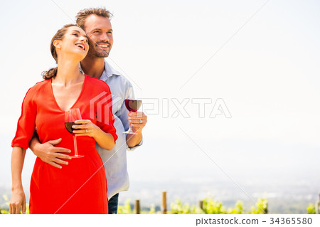 Smiling couple with red wine looking away Smiling couple with red wine looking away 34365580