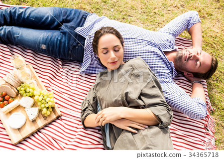 High angle view of couple sleeping on picnic blanket 34365718