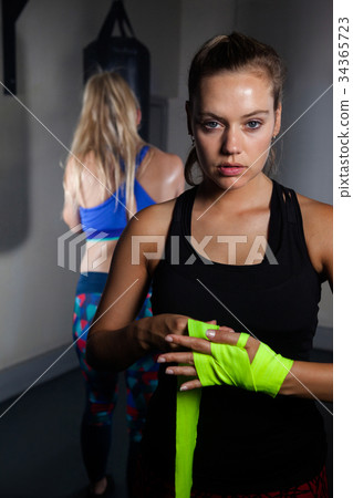 Woman tying hand wrap on hand in fitness studio 34365723