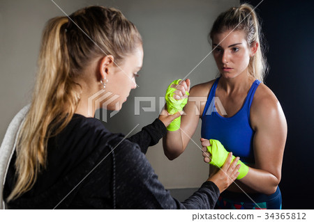 Trainer assisting woman in boxing 34365812