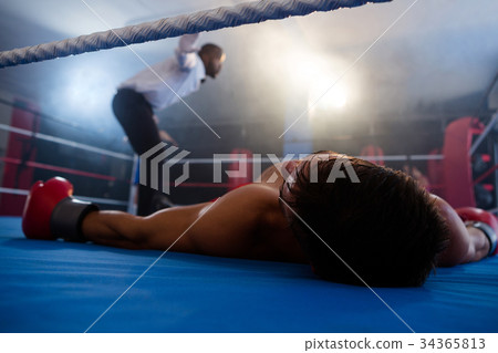Unconscious boxer lying by referee in ring Unconscious boxer lying by referee in ring 34365813