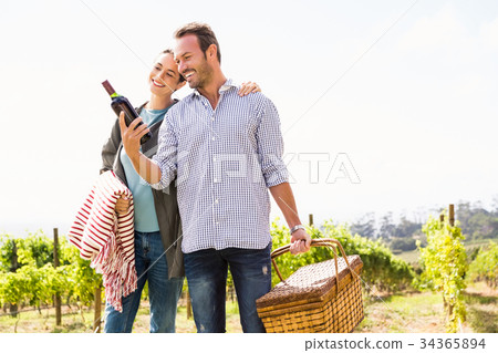 Man with woman holding wine bottle and basket 34365894