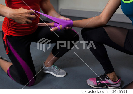 Trainer tying hand wrap on woman hand 34365911