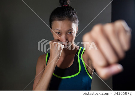 Determined woman practicing boxing in fitness studio Determined woman practicing boxing in fitness studio 34365972