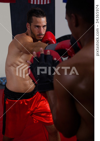 Trainer assisting man in boxing Trainer assisting man in boxing 34365974