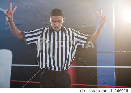 Young male referee gesturing while looking down in boxing ring Young male referee gesturing while looking down in boxing ring 34366006