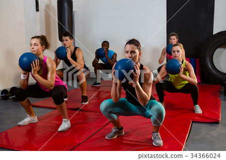 Young athletes crouching with exercise balls 34366024