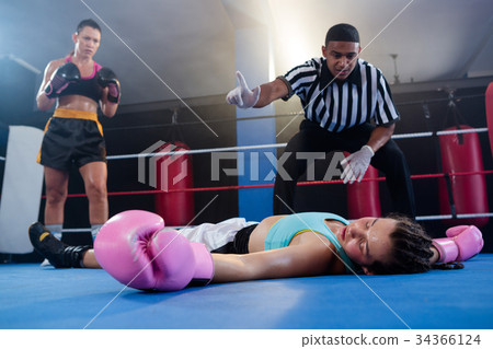 Female boxer looking while referee counting by athlete 34366124