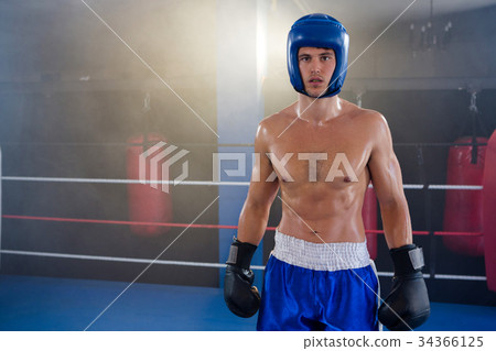 Portrait of confident shirtless boxer wearing protective sportsgear 34366125