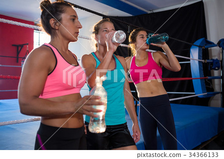 Exhausted young athletes drinking water by boxing ring 34366133