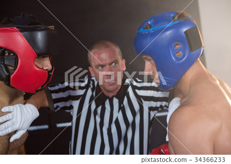 Referee stopping aggressive male boxers 34366233