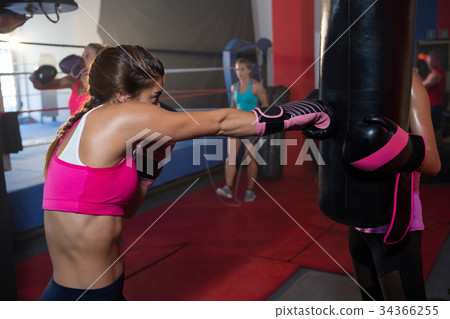 Young female boxer punching black bag 34366255