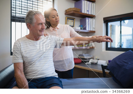 Female doctor and senior male patient looking at hand Female doctor and senior male patient looking at hand 34366269