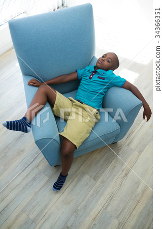 High angle view of boy lying on armchair at home High angle view of boy lying on armchair at home 34366351