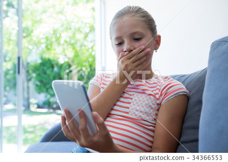 Girl with hands covering mouth holding phone Girl with hands covering mouth holding phone 34366553