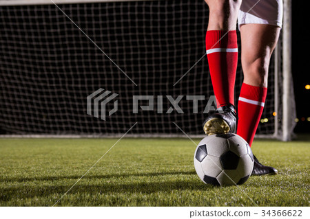 Low section of male soccer player with ball on field 34366622