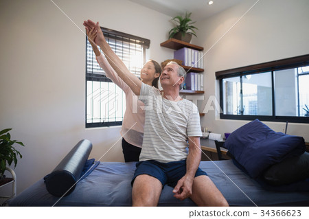 Smiling female doctor and male patient looking up with arms raised 34366623