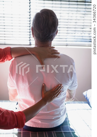 Rear view of senior male patient receiving back massage from female therapist 34366720