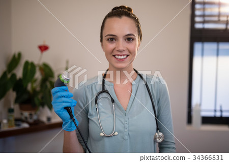 Portrait of smiling young female therapist holding ultrasound machine Portrait of smiling young female therapist holding ultrasound machine 34366831