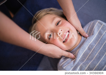 Portrait of smiling boy receiving neck massage from female therapist Portrait of smiling boy receiving neck massage from female therapist 34366904