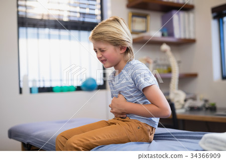 Boy sitting on bed with stomachache Boy sitting on bed with stomachache 34366909