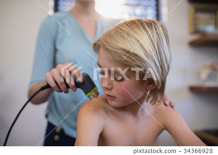 Boy looking at shoulder with female therapist using ultrasound scan 34366928