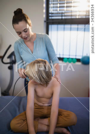 Female therapist scanning shoulder of shirtless boy with ultrasound machine Female therapist scanning shoulder of shirtless boy with ultrasound machine 34366934