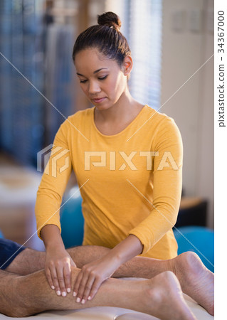 Female therapist massaging calf of senior male patient Female therapist massaging calf of senior male patient 34367000