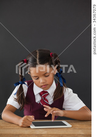 Schoolgirl using digital tablet against blackboard Schoolgirl using digital tablet against blackboard 34367079