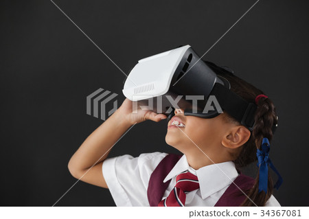 Schoolgirl using virtual reality headset against blackboard 34367081
