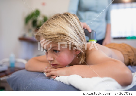 Close-up of boy lying on bed while female therapist using ultrasound machine 34367082