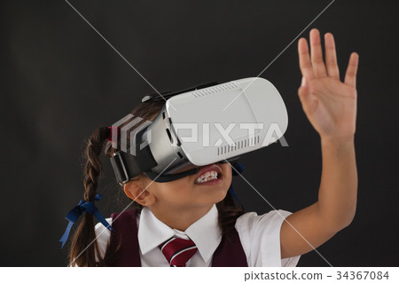 Schoolgirl using virtual reality headset against blackboard 34367084