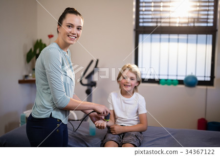 Portrait of smiling boy with female therapist scanning wrist Portrait of smiling boy with female therapist scanning wrist 34367122