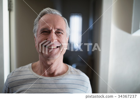 Close-up portrait of smiling senior male patient standing in corridor Close-up portrait of smiling senior male patient standing in corridor 34367237