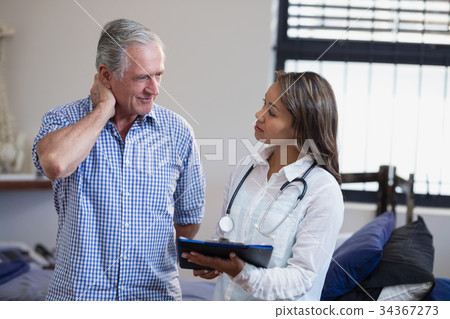 Senior male patient and female therapist discussing file against window Senior male patient and female therapist discussing file against window 34367273