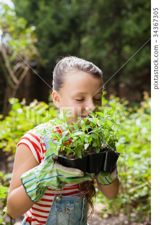 Girl smelling plants with eyes closed Girl smelling plants with eyes closed 34367305