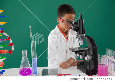 Smiling schoolboy looking through microscope in laboratory Smiling schoolboy looking through microscope in laboratory 34367335