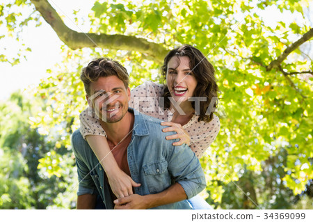 Happy man giving piggy bag to woman on a sunny day Happy man giving piggy bag to woman on a sunny day 34369099
