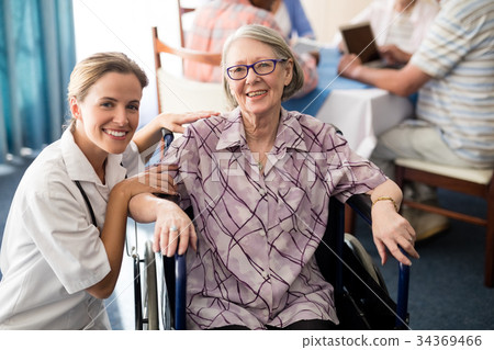 Portrait of smiling female doctor with disabled senior woman sitting on wheelchair Portrait of smiling female doctor with disabled senior woman sitting on wheelchair 34369466