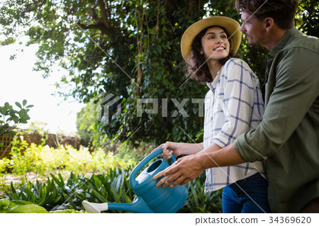 Romantic couple watering plants with watering can in garden 34369620
