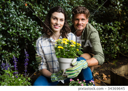 Couple holding sapling plant in garden 34369645