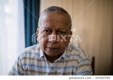 Portrait of senior man sitting by window 34369760