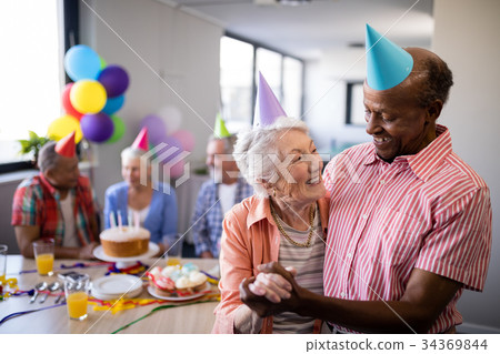 Happy senior couple wearing party hats with friends 34369844