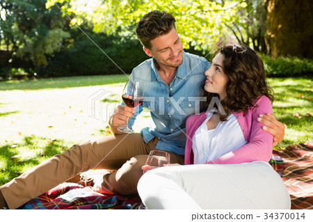 Romantic couple having glass of wine in park Romantic couple having glass of wine in park 34370014